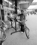 858424 Afbeelding van een meisje dat een bak met grammofoonplaten bekijkt bij de platenwinkel van Max van Praag in het ...